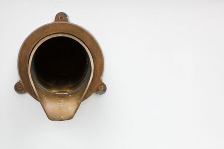 Brass fixture on side of city building with spout for rain water drainage