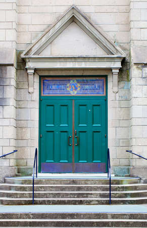 Steps leading to the double green doors of a Catholic church with a stone triangle featureの写真素材