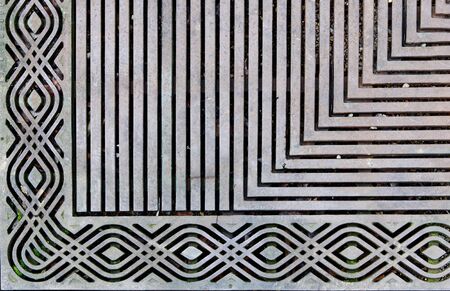 Corner of an ornately designed steek grating on the sidewalkの写真素材