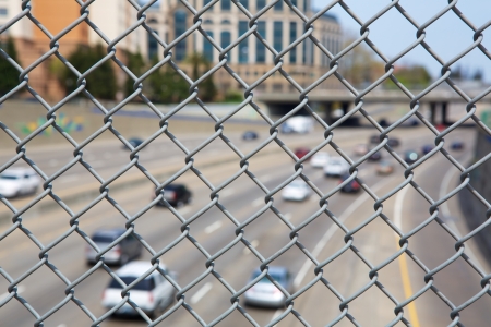 Narrow Dept of Field close up image of chain link fence with out of focus highway and cars