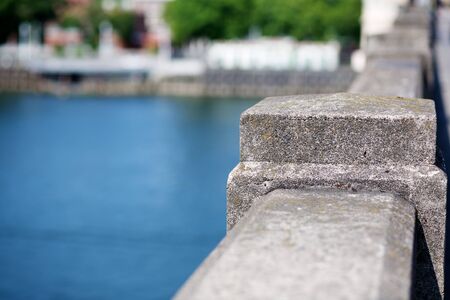 Concrete Bridge Railing with river and city shoreline visible in soft focusの写真素材