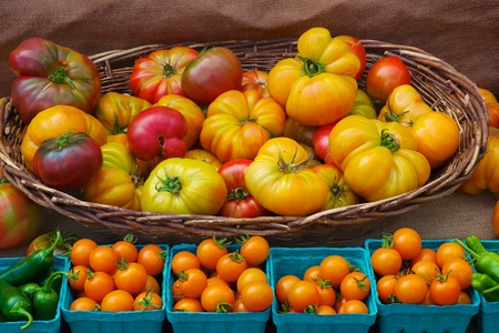 Baskets of heritage and cherry tomatoes with green peppers on a rough canvas backgroundの写真素材