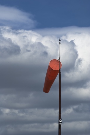 Windsock on mast against cloudy sky