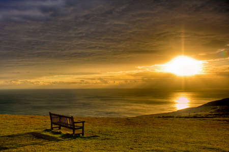 Glorious sunset over the Isle of White looking out to see with a bench in the foregroundの写真素材