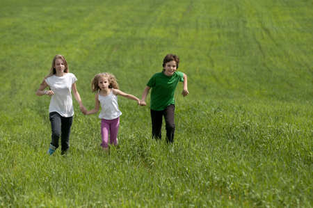 Children running on green meadow field の写真素材