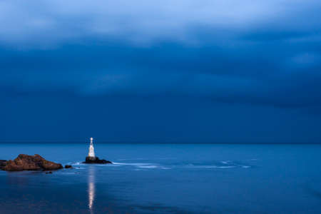 Nightly seascape with lighthouse and moody skyの写真素材