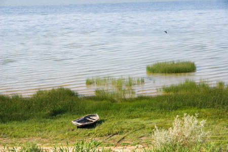 Old boat on the grass near the waterの写真素材