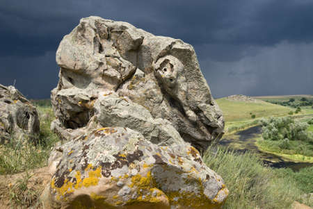 Boulder on the fantastically shaped background of a stormy skyの写真素材