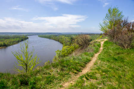 View of the Don bend from a height. Green spring banks are visible, in the foreground is a tree with freshly blossoming green foliageの写真素材