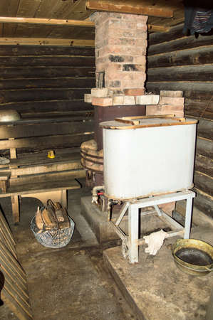 Rustic bathhouse inside with wood stove and basinの写真素材