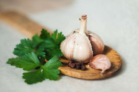 Baked garlic, fresh herbs, and clove on a wooden cooking spadeの写真素材