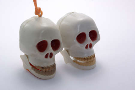 Two human toy rattle jaw skulls with golden teeth on white.の写真素材