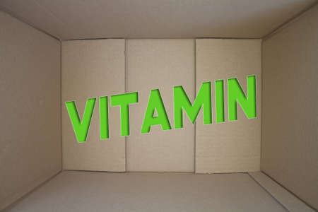 Vitamin word with cardboard box. Brown folded cardbox.