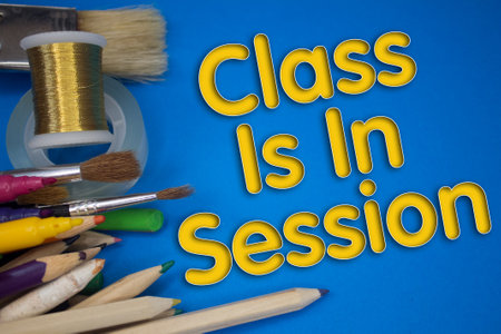 Overhead shot of school supplies with Class Is In Session text. Brushes, pencils, artistic tools....