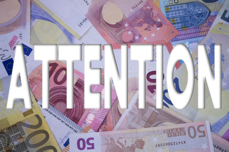 Attention word with money. Paper currency background with different banknotes.の写真素材