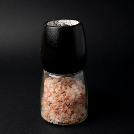 Himalayan pink salt in a glass bottle on a black backgroundの写真素材