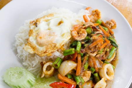 Spicy seafood fried with fried egg and riceの写真素材