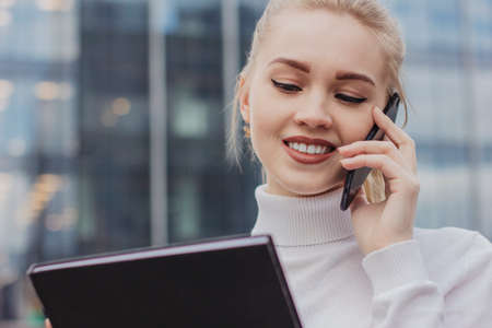 Close-up of smiling attractive girl with white hair while sitting outdoors near a business centerの写真素材