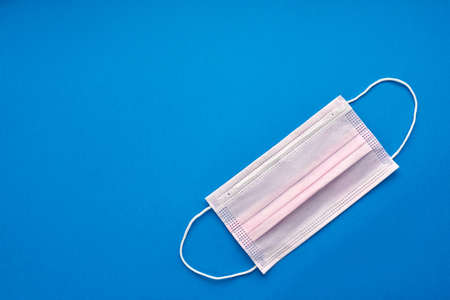 coronavirus COVID-19 pandemic. antiviral medical mask for protection against corona virus. Surgical protective mask. Medical respiratory bandage face on white background. quarantine, stay at home. on blue backgroundの写真素材