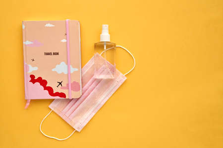 Coronavirus travel concept. Face Mask Medical Protective and Travel book.Covid-19 novel coronavirus outbreak on yellow background.Protect Coronavirus,Covid-19 and pm 2.5. On Wooden table. Copy spaceの写真素材