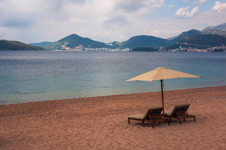 Sunbeds and umbrella on the beach on the Adriatic sea near Budva, Montenegroの写真素材