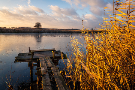 Autumn landscape with a wooden footbridge and the setting sun at the lake near Konstancin-Jeziorna, Masovia, Polandの写真素材