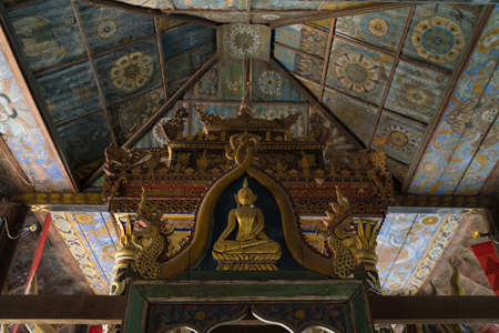 Wood carving buddha Statue with thai painting ceiling background Sri Nuan Sawang Arom Temple, Ubon Ratchathaniのeditorial素材