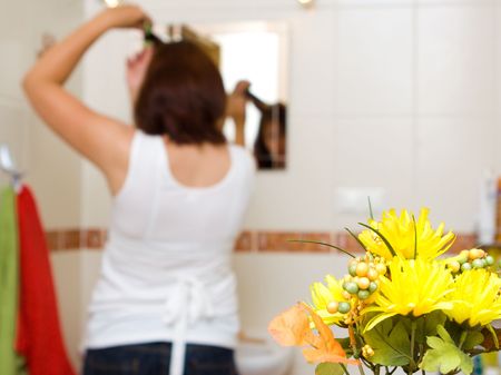 Woman in the mirror drying hairの写真素材