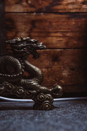side view of figurine of Chinese metal dragon, wooden backgroundの写真素材