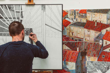 Concentrated male artist is drawing a dog on easel in his art studio, colorful pictures, creative atmosphereの写真素材