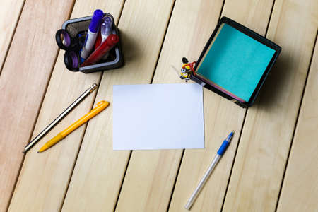 top view of mock up card on wooden table among  different stationary, pens, pencilsの写真素材