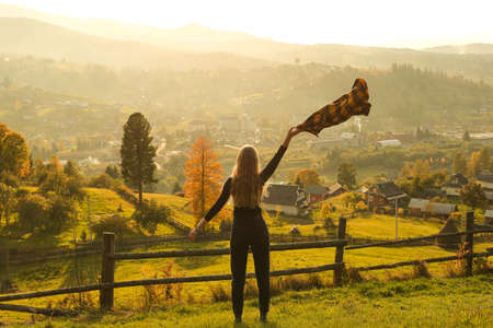 Beautiful girl with scarf on the background of the mountains in autumnの写真素材