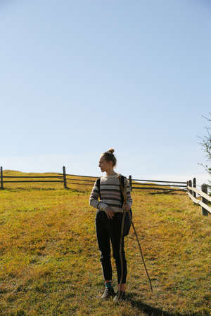Young woman with walking poles in field, back view. Space for textの写真素材
