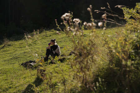 A woman sits on a green meadow.の写真素材