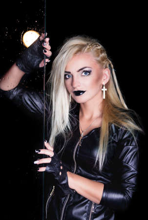 Portrait of pretty sexy young woman in leather jacket with water drops and flash light. Water studio...
