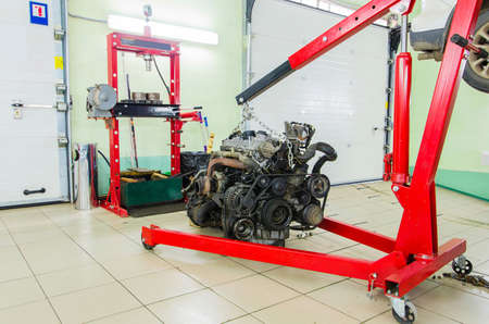 Motor engine on elevator in workshop car service station hanging up
