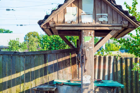 Wooden well near wooden fence with adsの写真素材