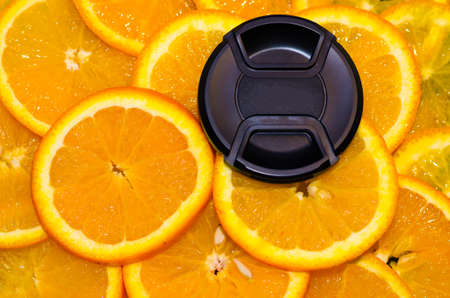 Lens cover lying on cute delicious oranges.の写真素材