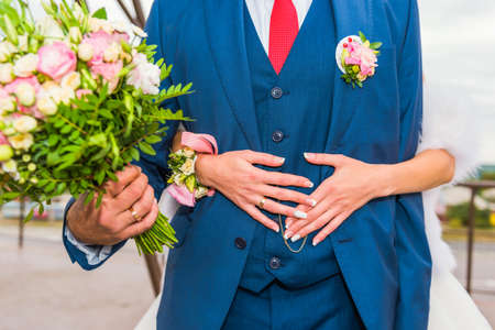 Groom hugs bride with bouquet of beautiful flowers.の写真素材