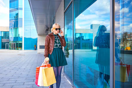 Shopping beautiful woman with bags making phone call on the streetの写真素材