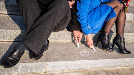 Couple drawing heart on concrete floor with chalkの写真素材