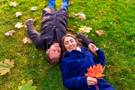 Couple lying on grass with leaves and laughingの写真素材