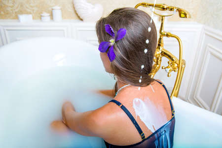 Milk is pouring on women shoulders in bathtubの写真素材