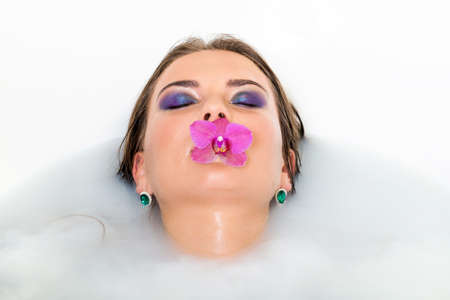 Beautiful woman keeps pink lily in her mouth