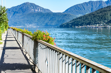 Panoramic landscape summer view of beautiful serene blue Lugano lake under clear blue sky surrounded by mountains on sunny day in Morcote, Switzerland, selective focusの写真素材