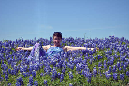 A women sitting in a field of blue bonnets.の写真素材