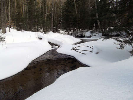 Small creek running through snow in winterの写真素材
