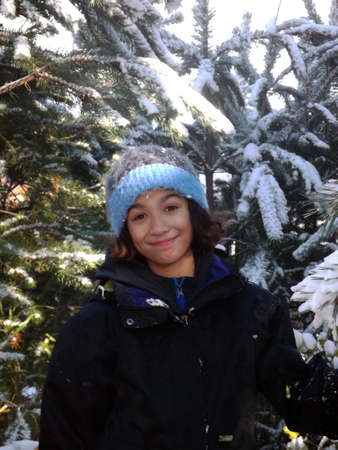 Teenager in winter clothing standing among snowy Christmas treesの写真素材