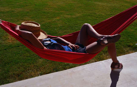 Teen girl laying in hammock with face coverd by a hatの写真素材