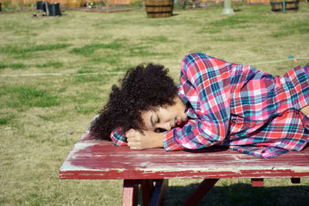 Cute teen girl sleeping on picnic tableの写真素材